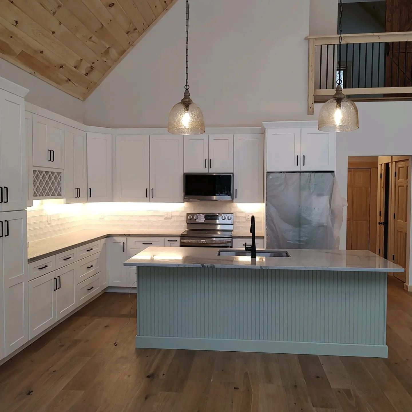 A kitchen with white cabinets and a large island in the middle.