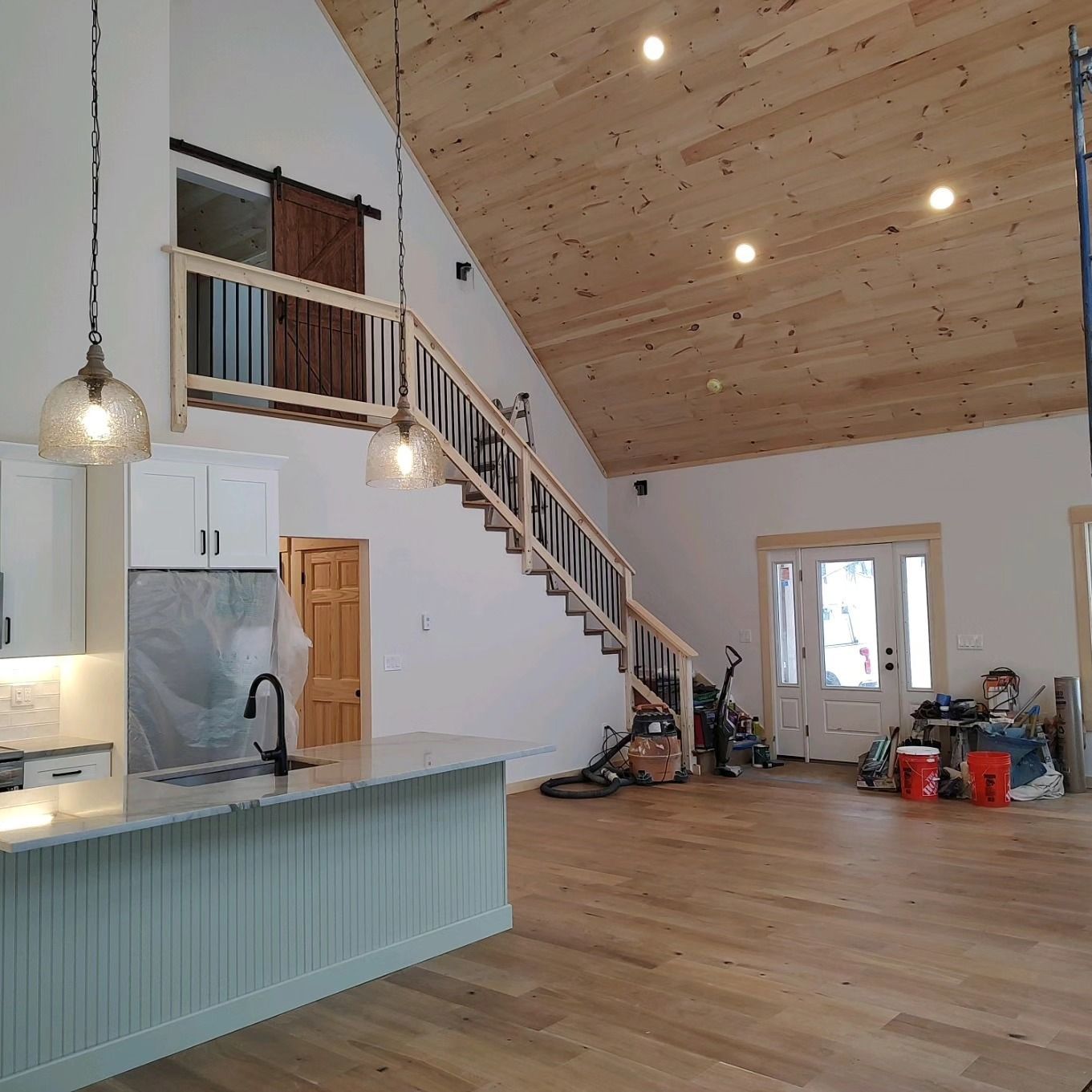 A kitchen with a wooden staircase leading up to the second floor.