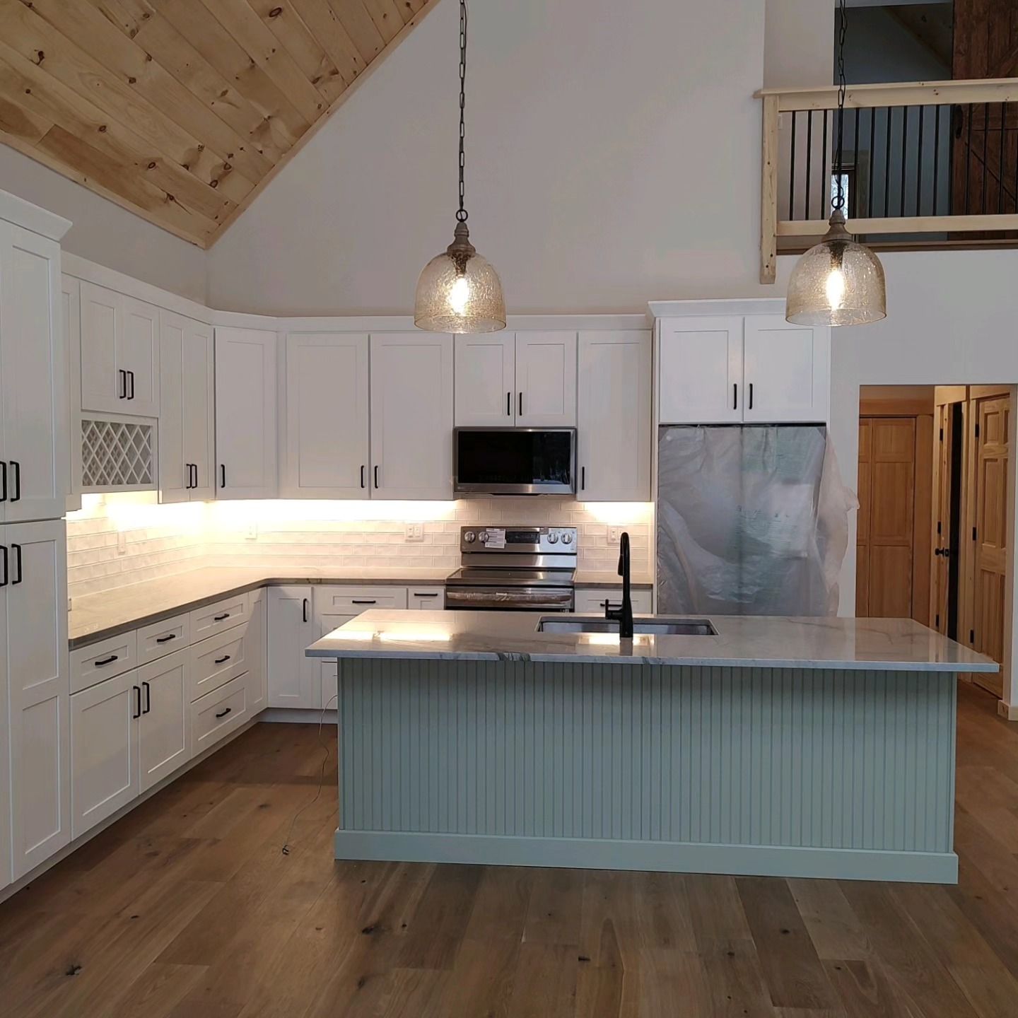 A kitchen with white cabinets , stainless steel appliances , and a large island.
