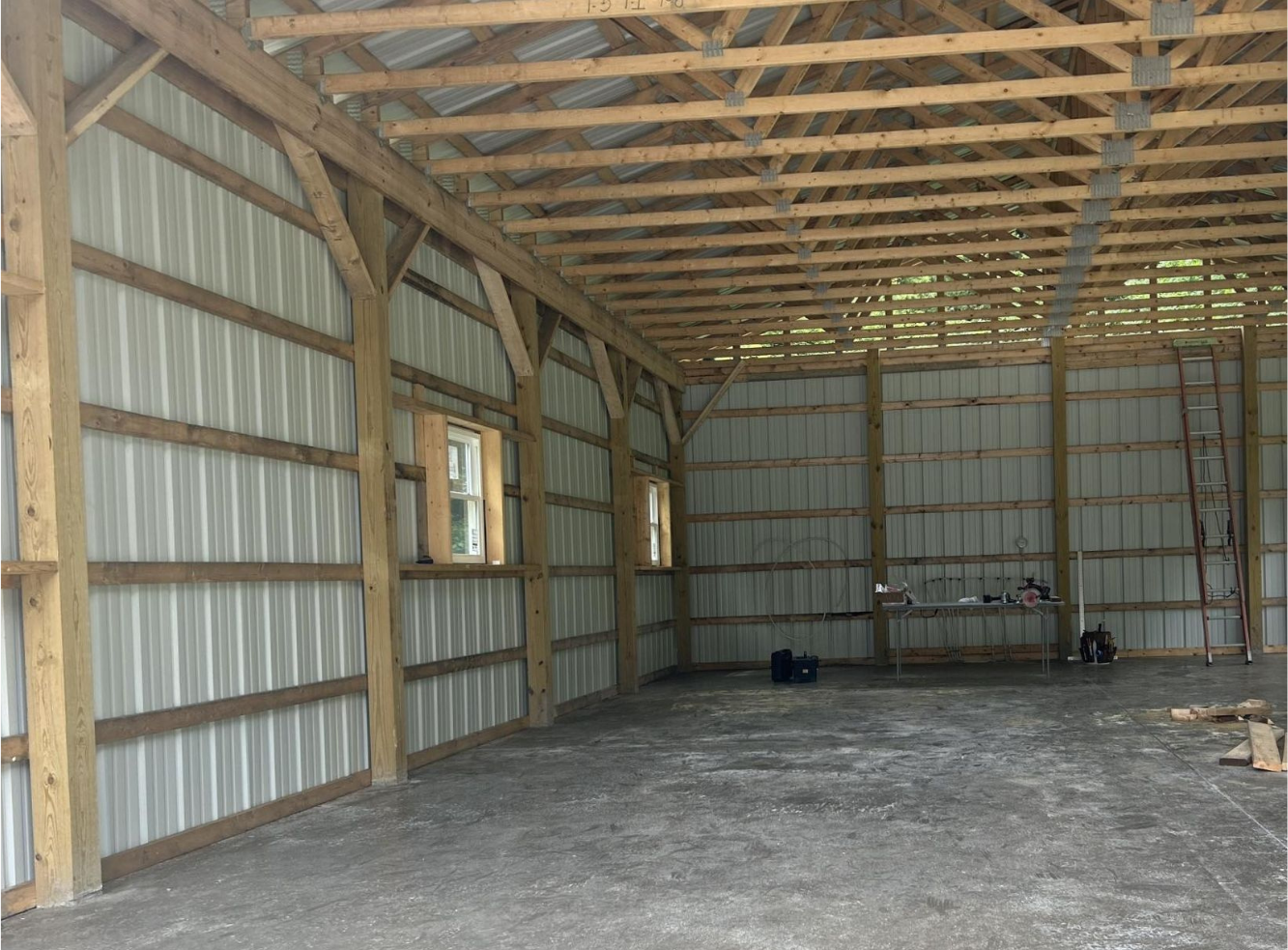 The inside of a barn with wooden beams and a concrete floor.