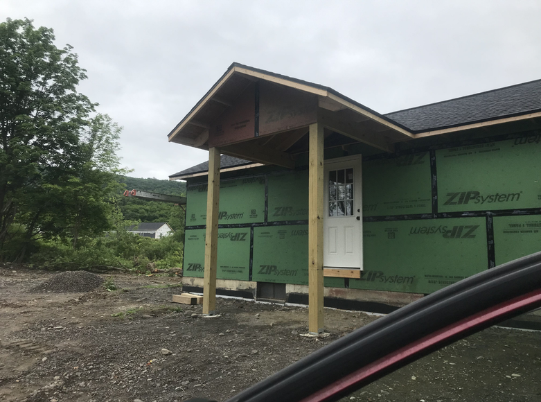 A house under construction with a porch and a door