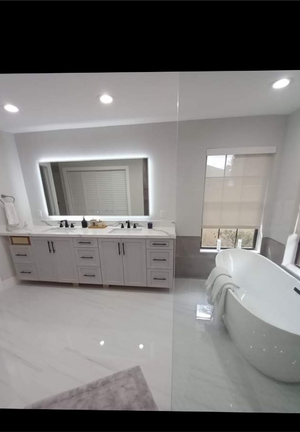 A bathroom with a tub , sink , mirror and window.