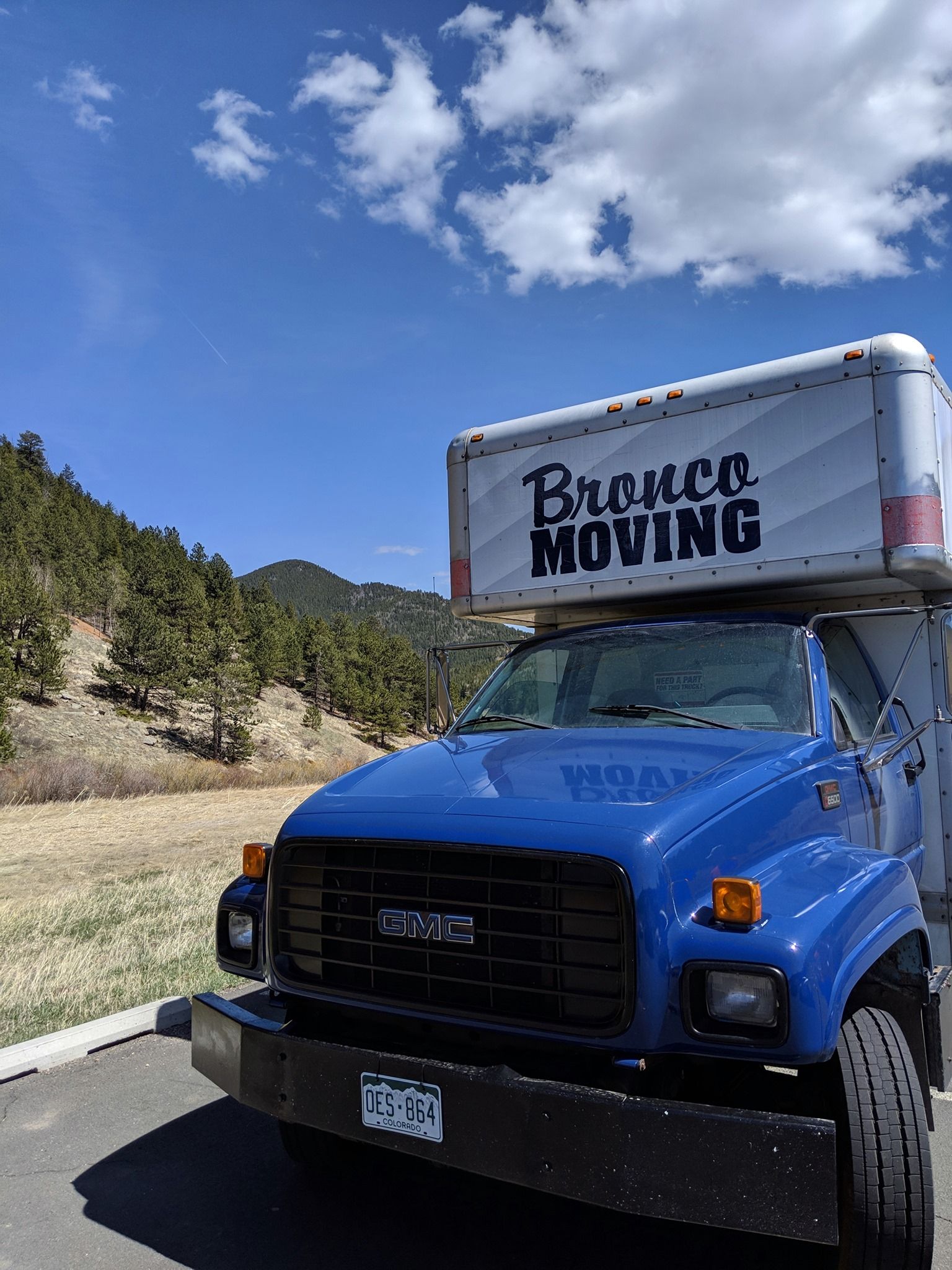 Moving truck with Bronco Moving logo on a road.