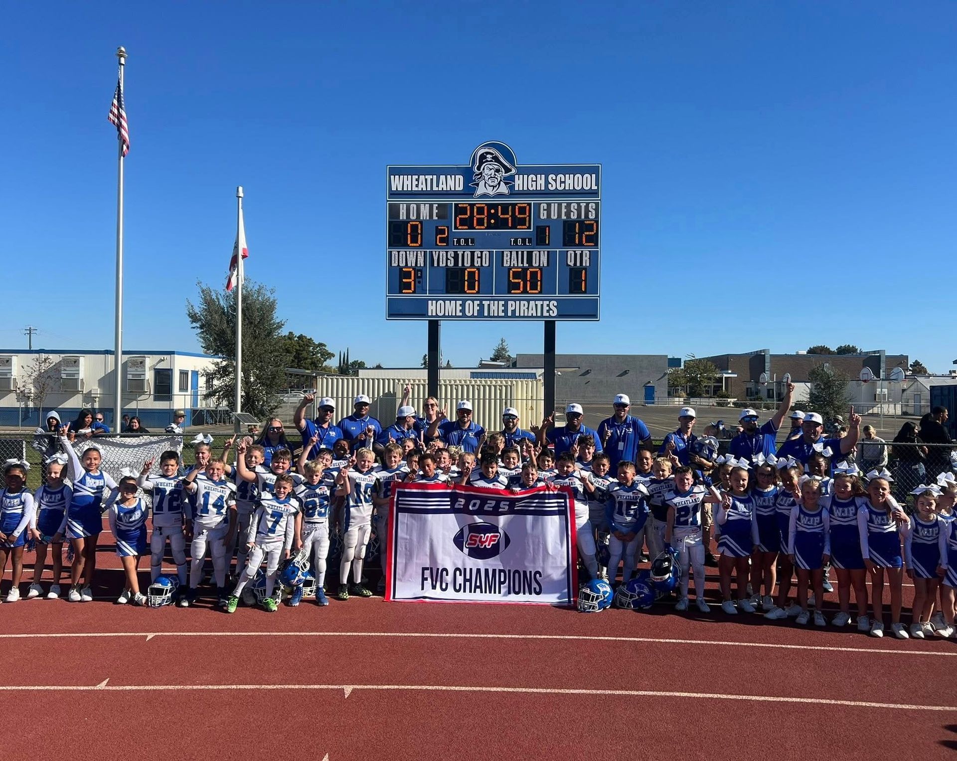 Football players in action on a grassy field; one runs with the ball, pursued by two opponents.