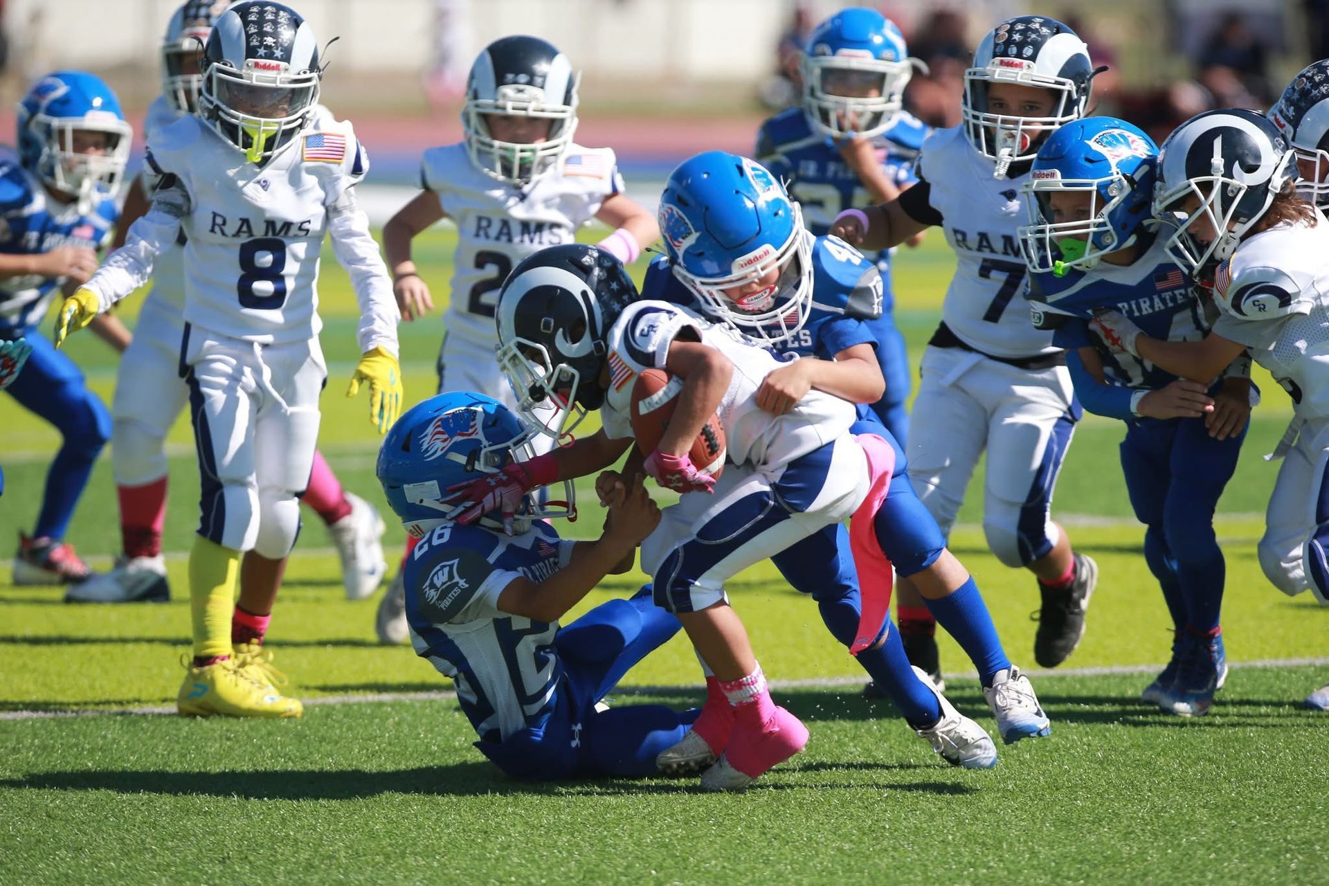 Football player in silver uniform runs with ball on a green field.
