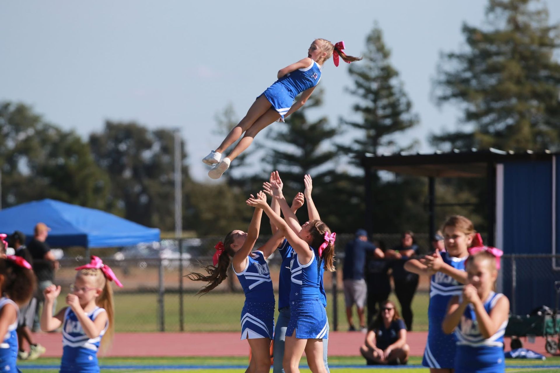 Cheerleader in red uniform performs a backbend on a green and red football field.