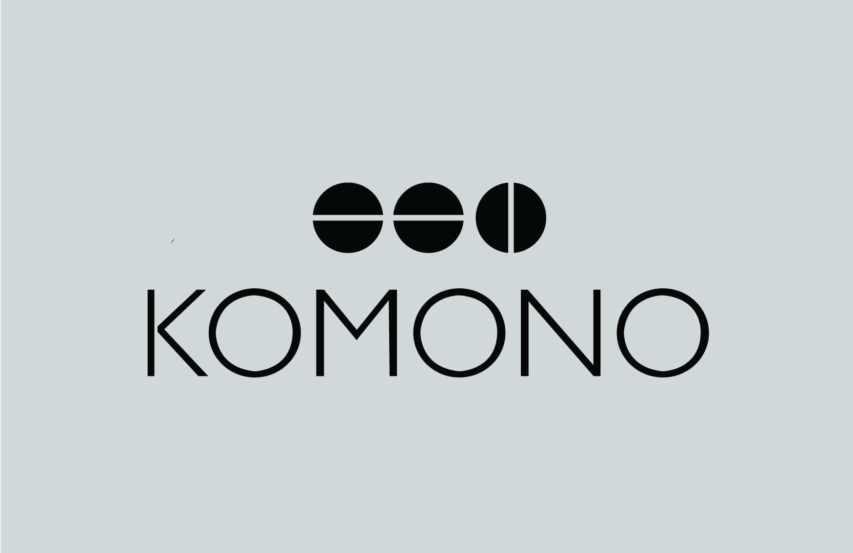 Een zwart-wit logo voor komono op een grijze achtergrond.