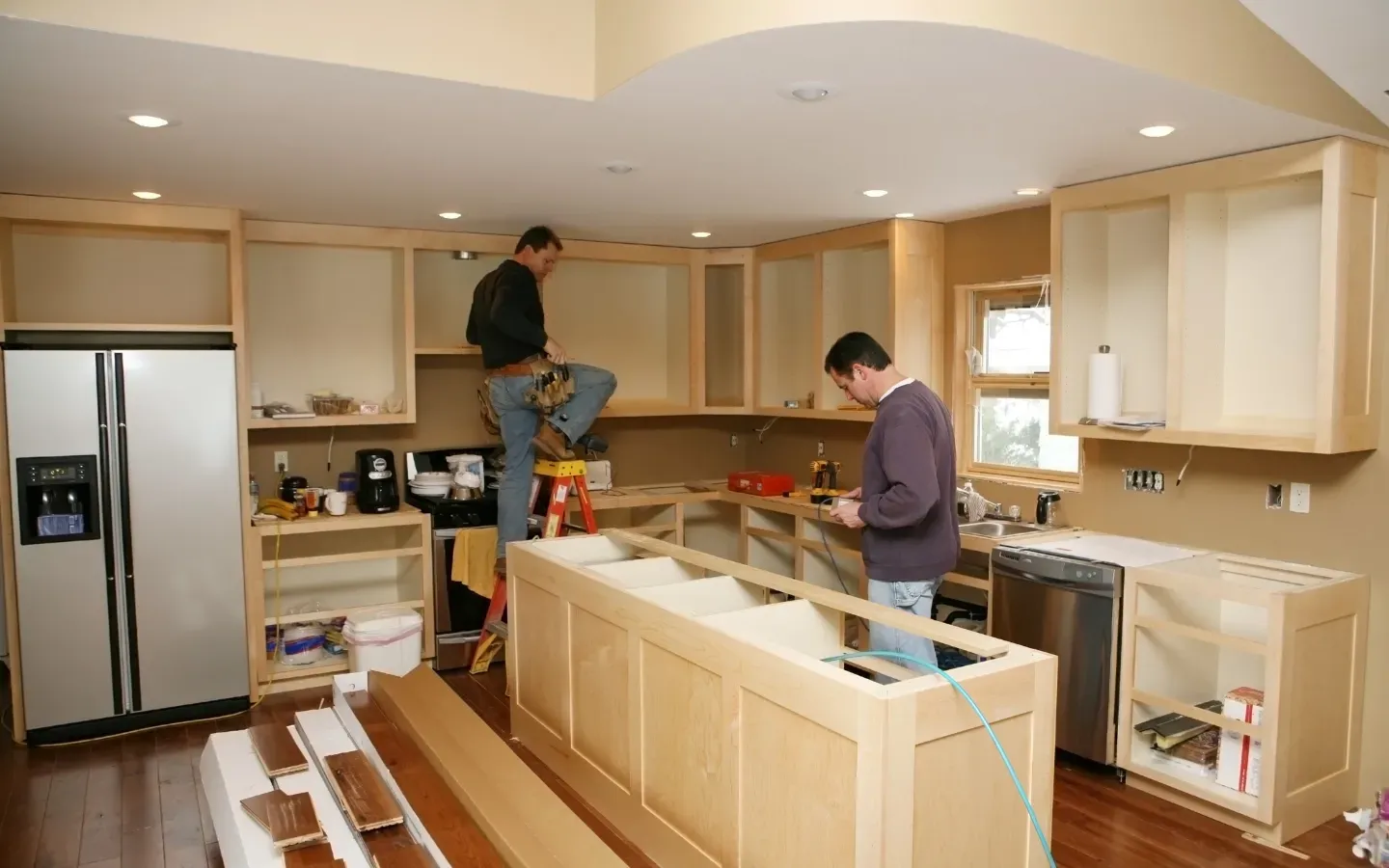 Two men are working on a kitchen in a house