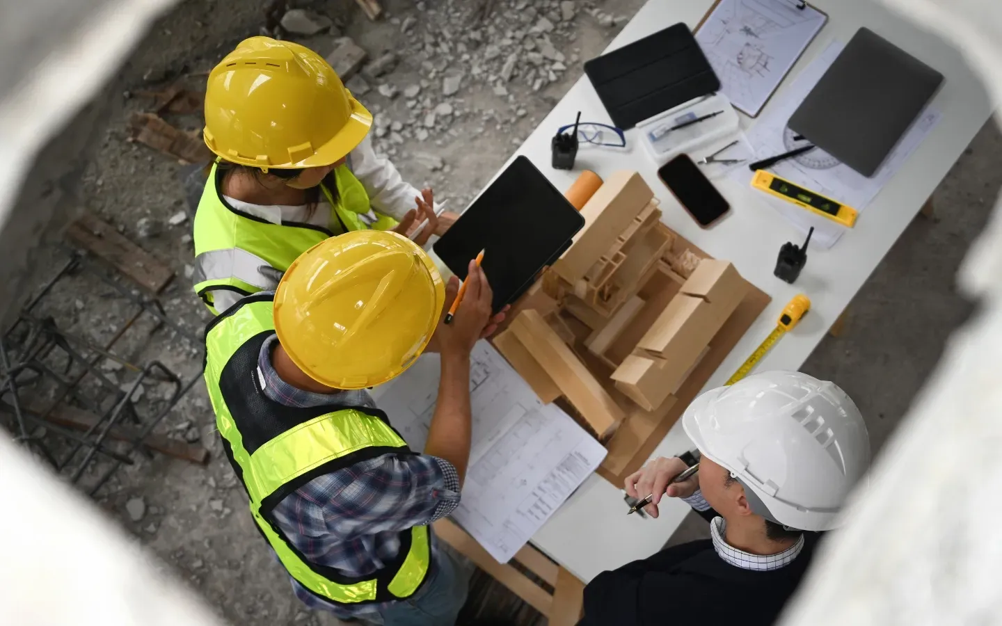 A group of construction workers are sitting around a table looking at a tablet.