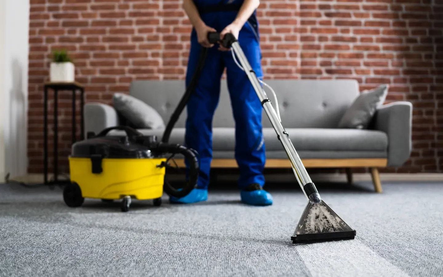 A man is cleaning a carpet with a vacuum cleaner in a living room.