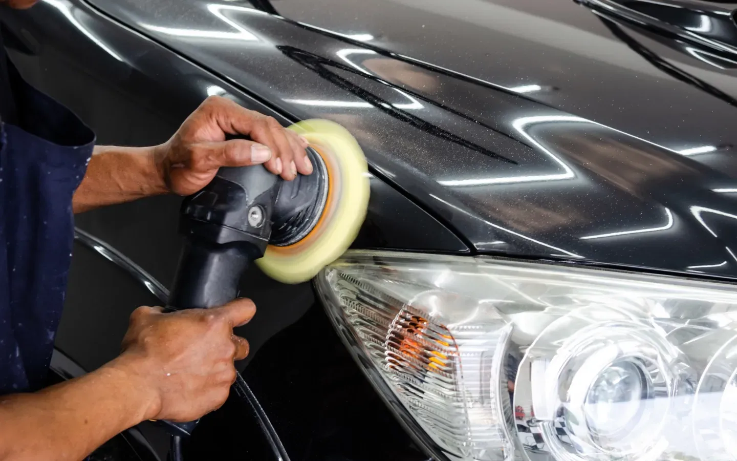 Israel Inc. - A man is polishing the hood of a car with a polisher.