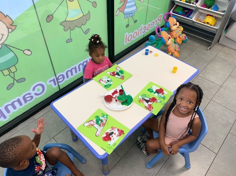 A group of children are sitting at a table in a room.