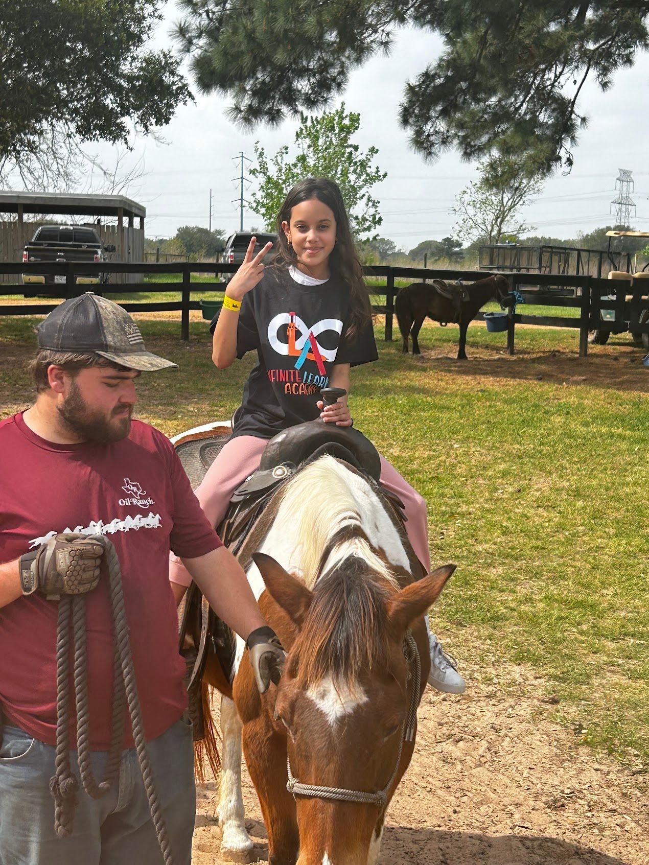 A little girl is riding a horse with a man standing behind her.
