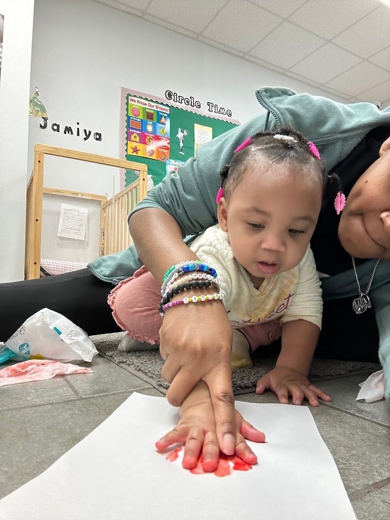 A woman is laying on the floor with a baby.