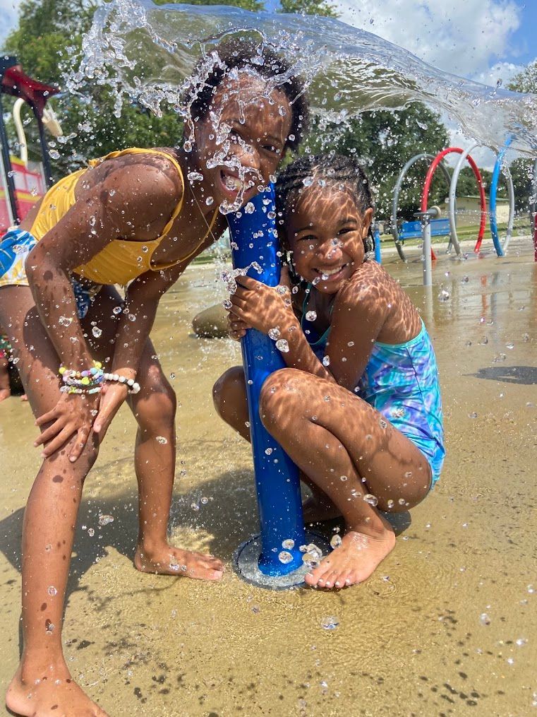Two young girls are playing in a water park.