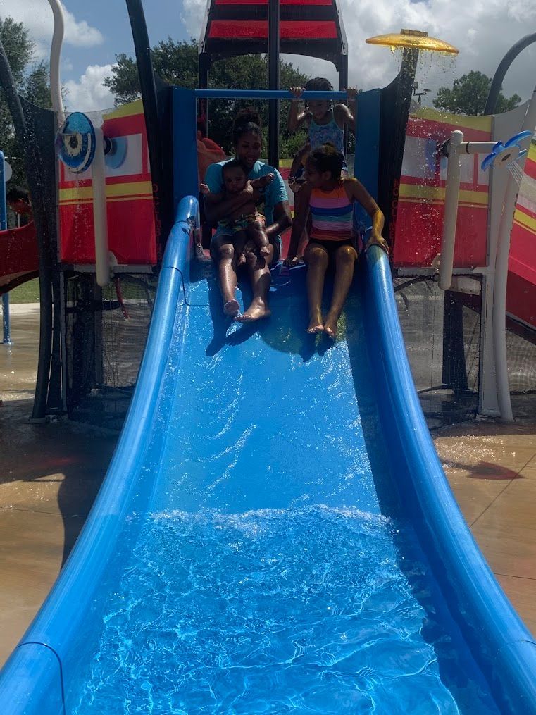 A group of children are riding down a blue water slide.