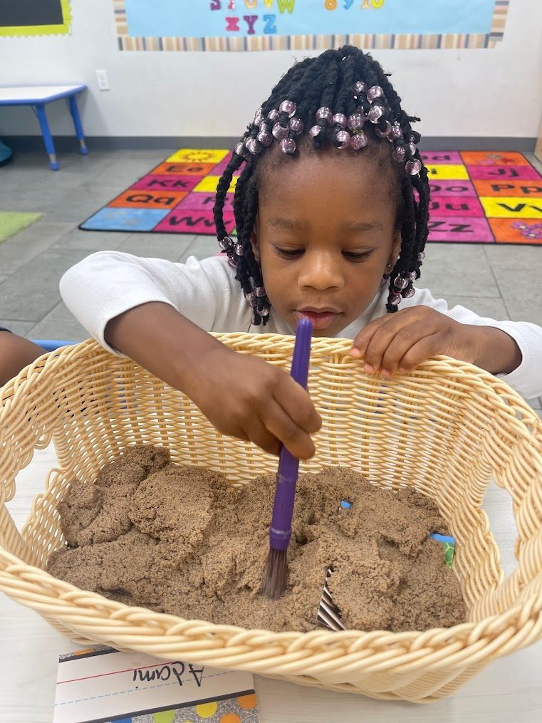 A little girl is playing with sand in a basket