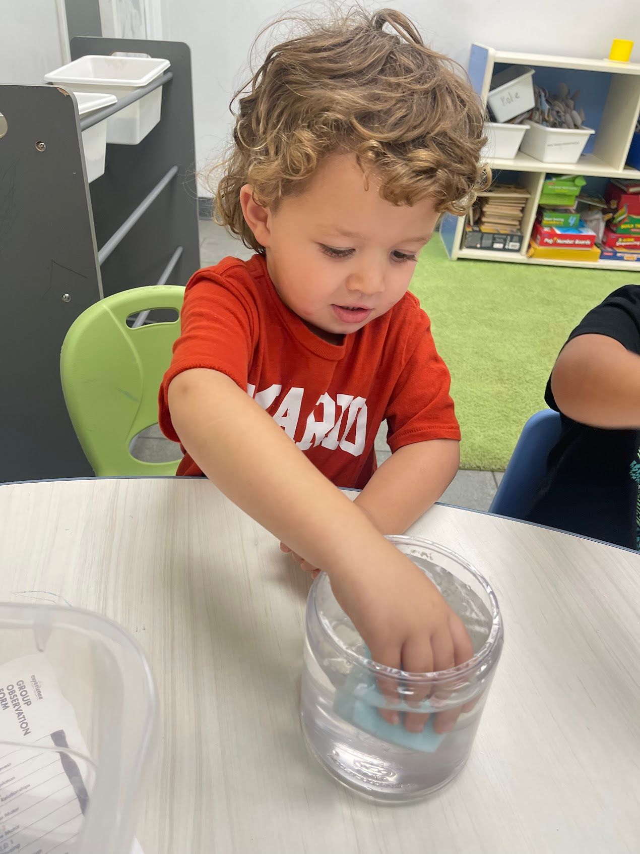 A young boy is playing with a jar of water.