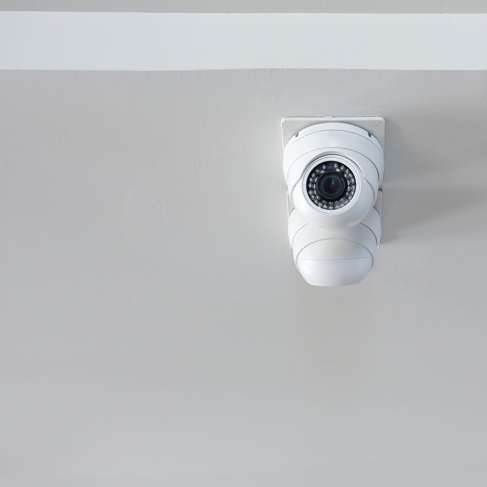 A surveillance camera mounted to a white wall.