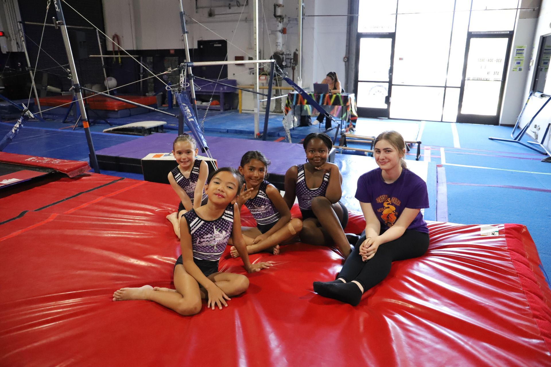 A group of people are sitting in a circle on the floor in a gym.