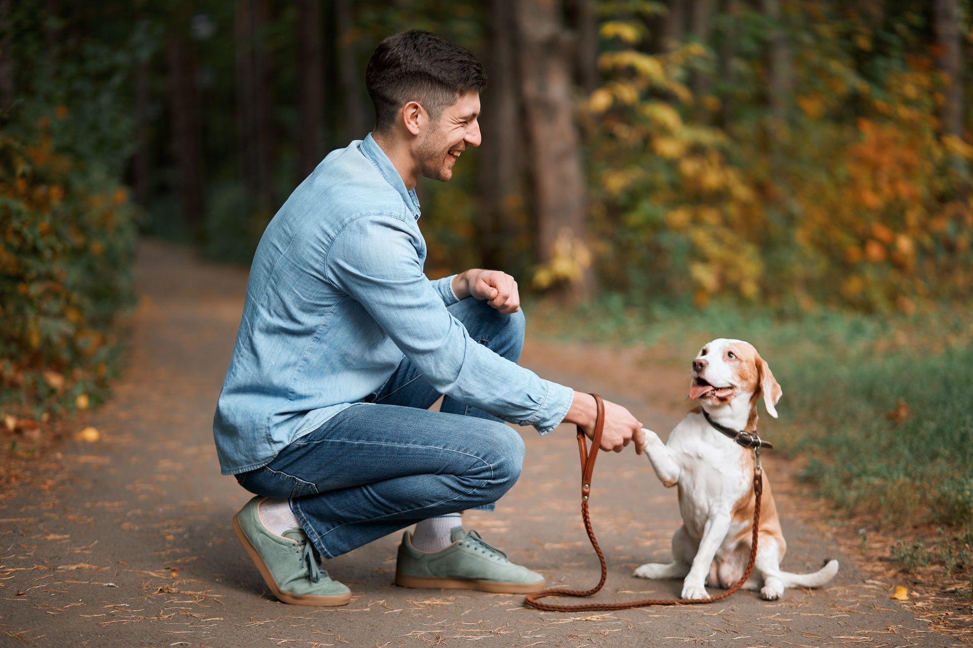 A man is kneeling down next to a dog in a field.
