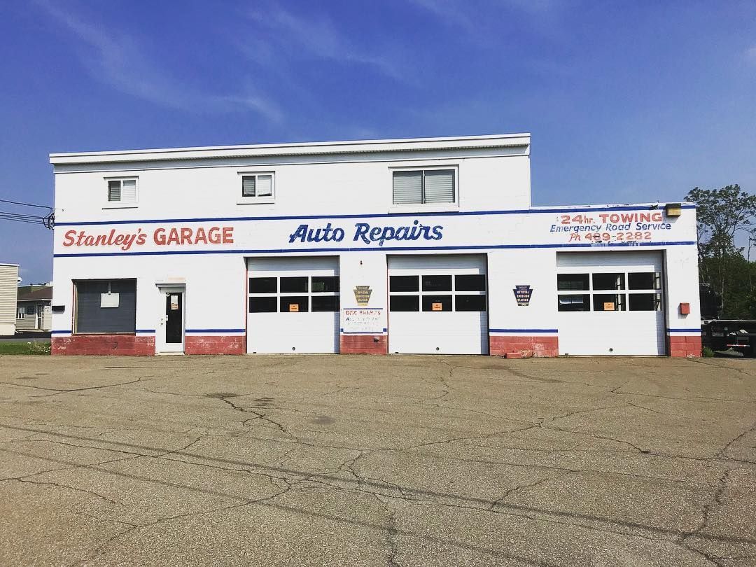 Stanley's Garage, white building with blue and red trim, three garage bays, and signage for auto repairs.
