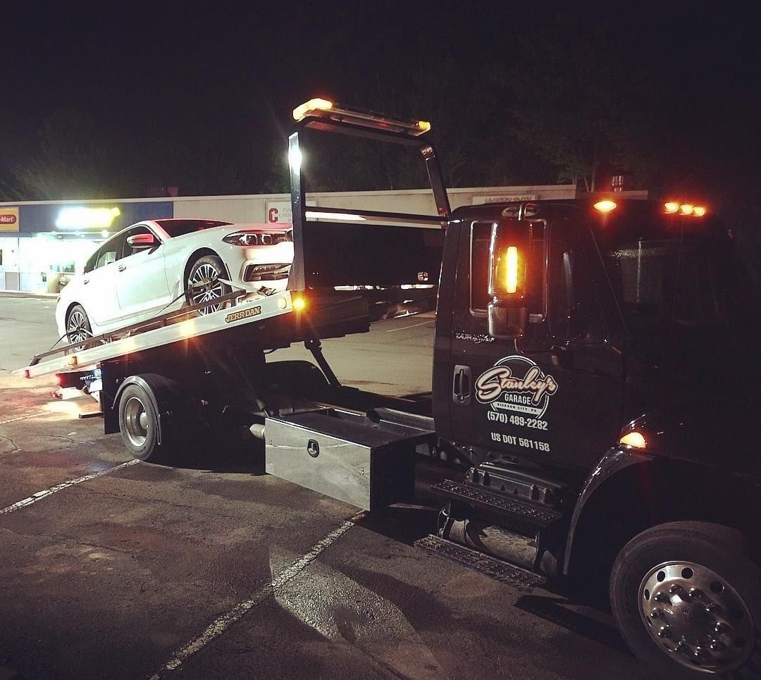 Tow truck loading a white car at night.