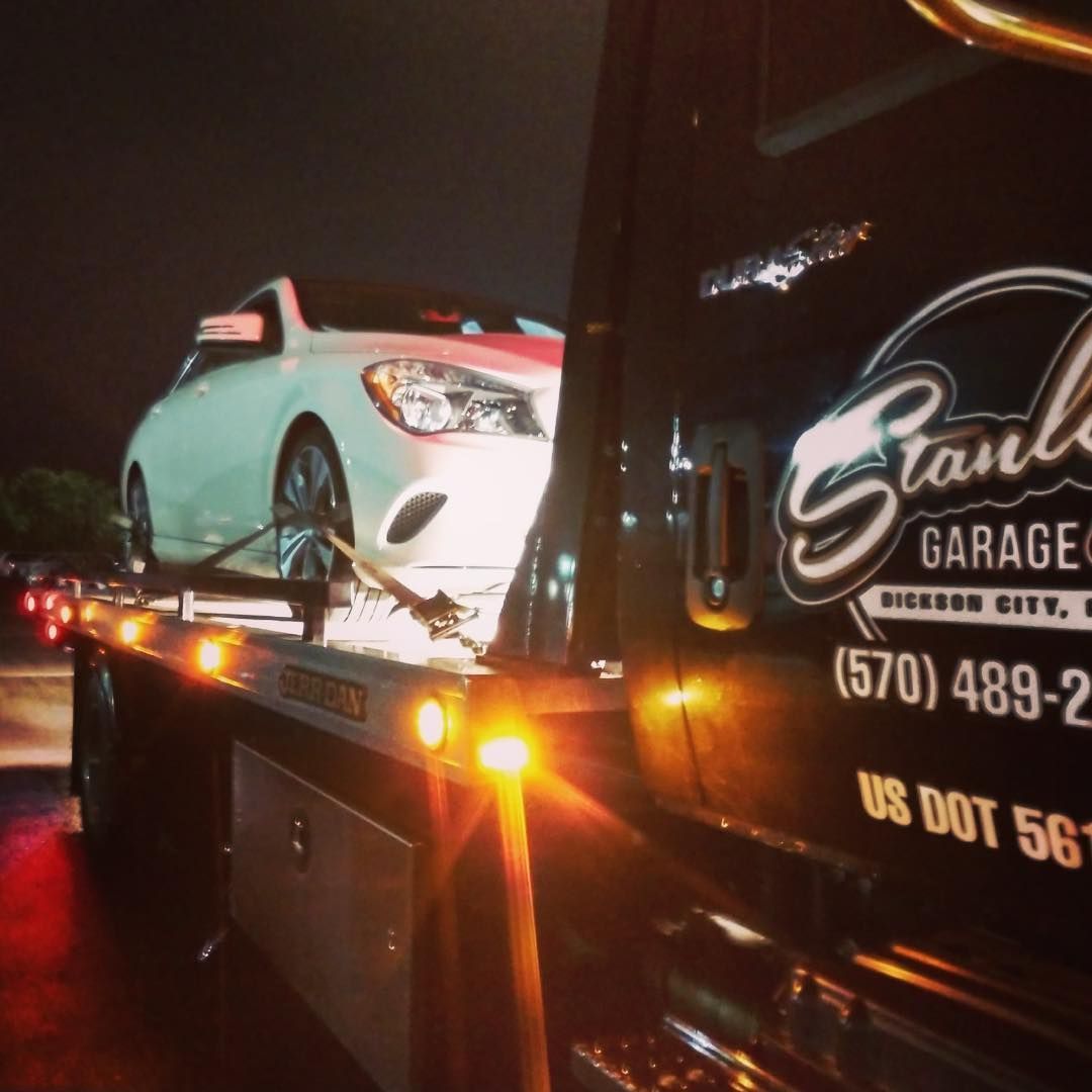 White car on a tow truck at night. Tow truck has 