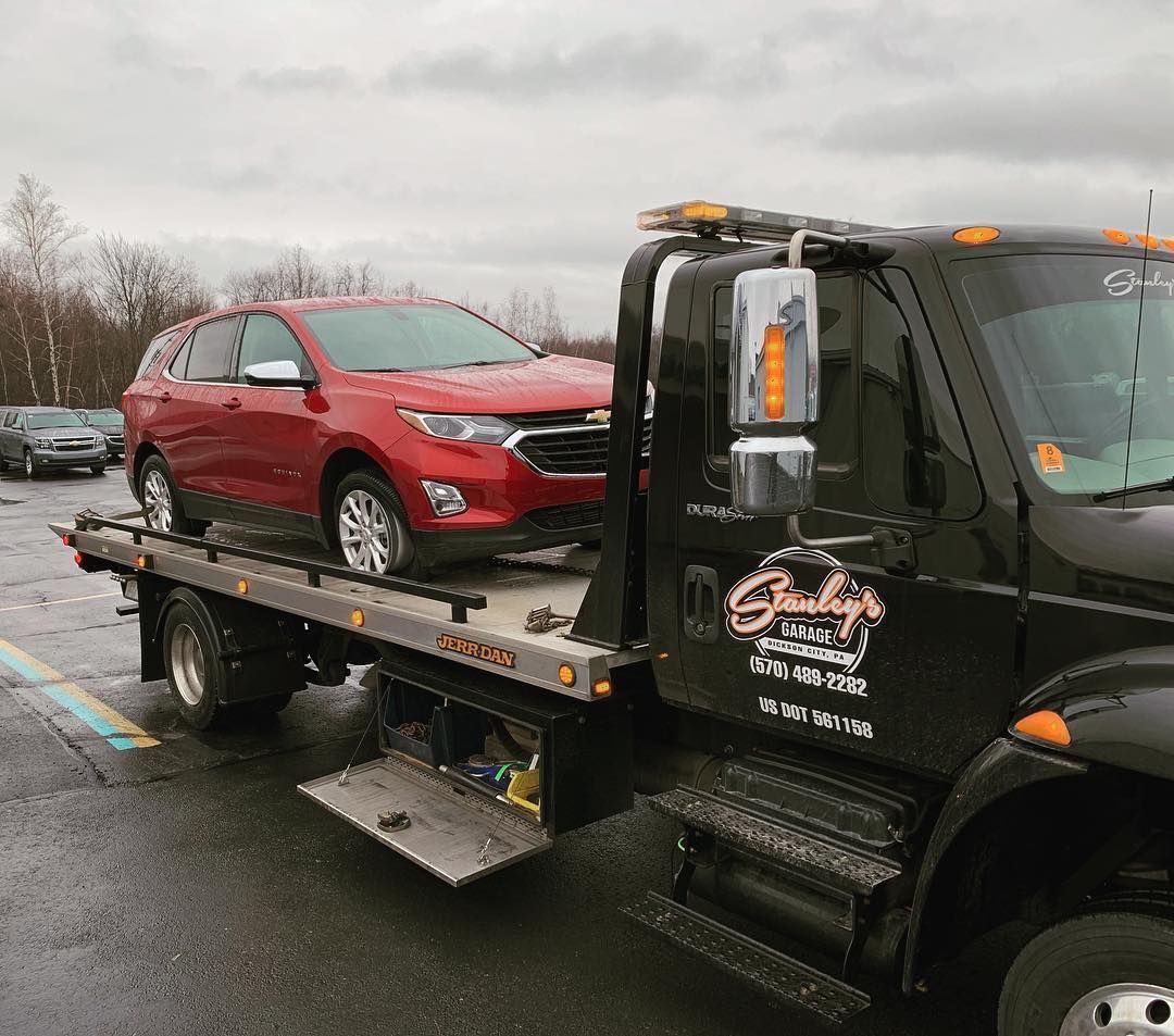 Red SUV being towed on a flatbed tow truck in a parking lot.