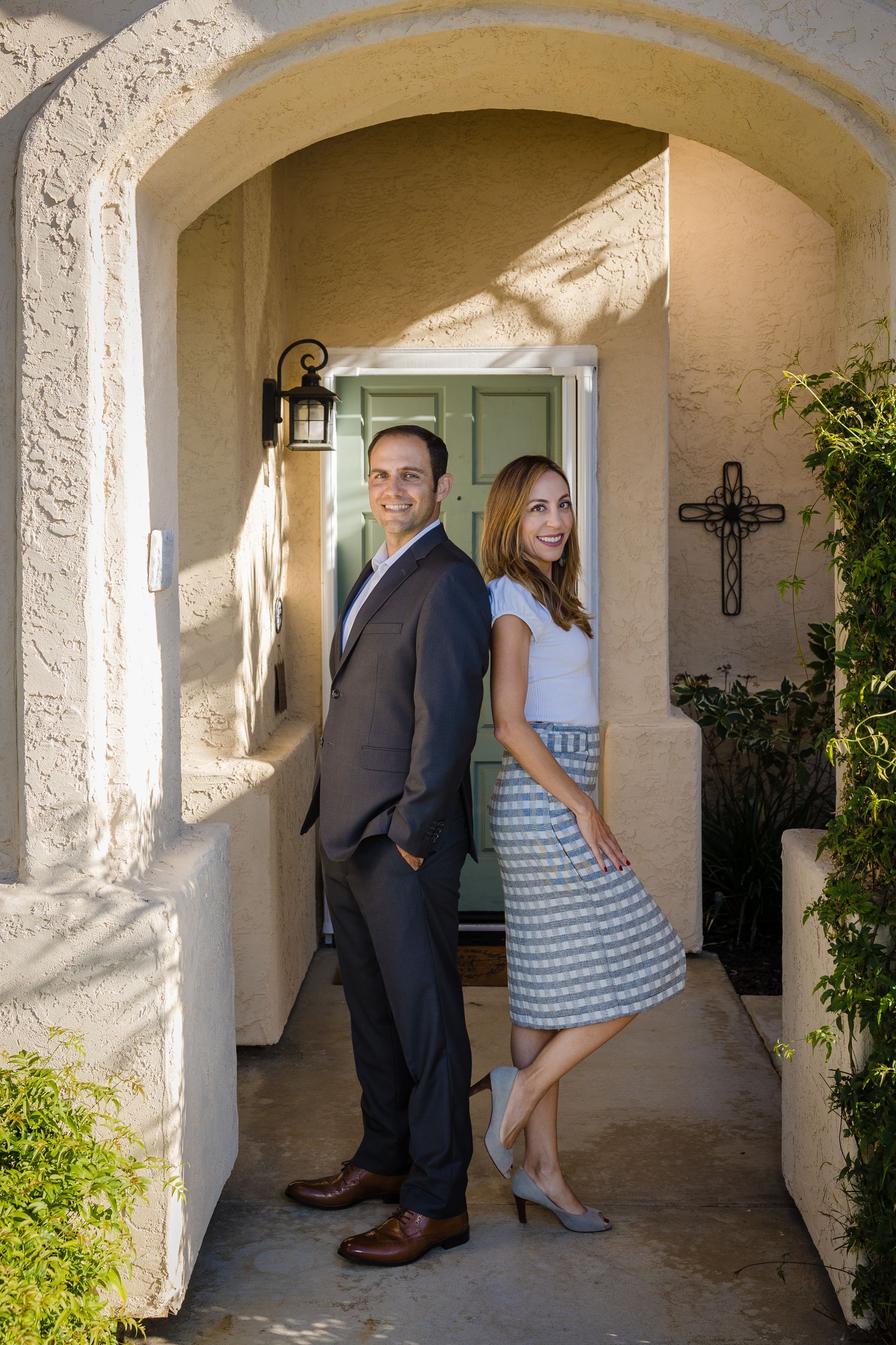 A woman is sitting at a desk with a laptop and a vase of flowers.