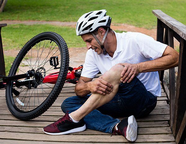 bicyclist holding his knee after a fall