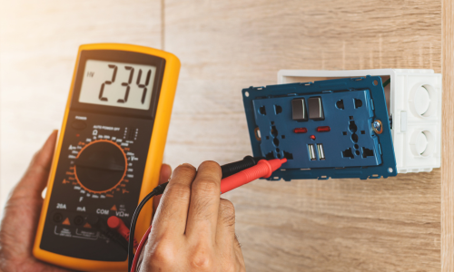 A person is using a digital multimeter to check a socket