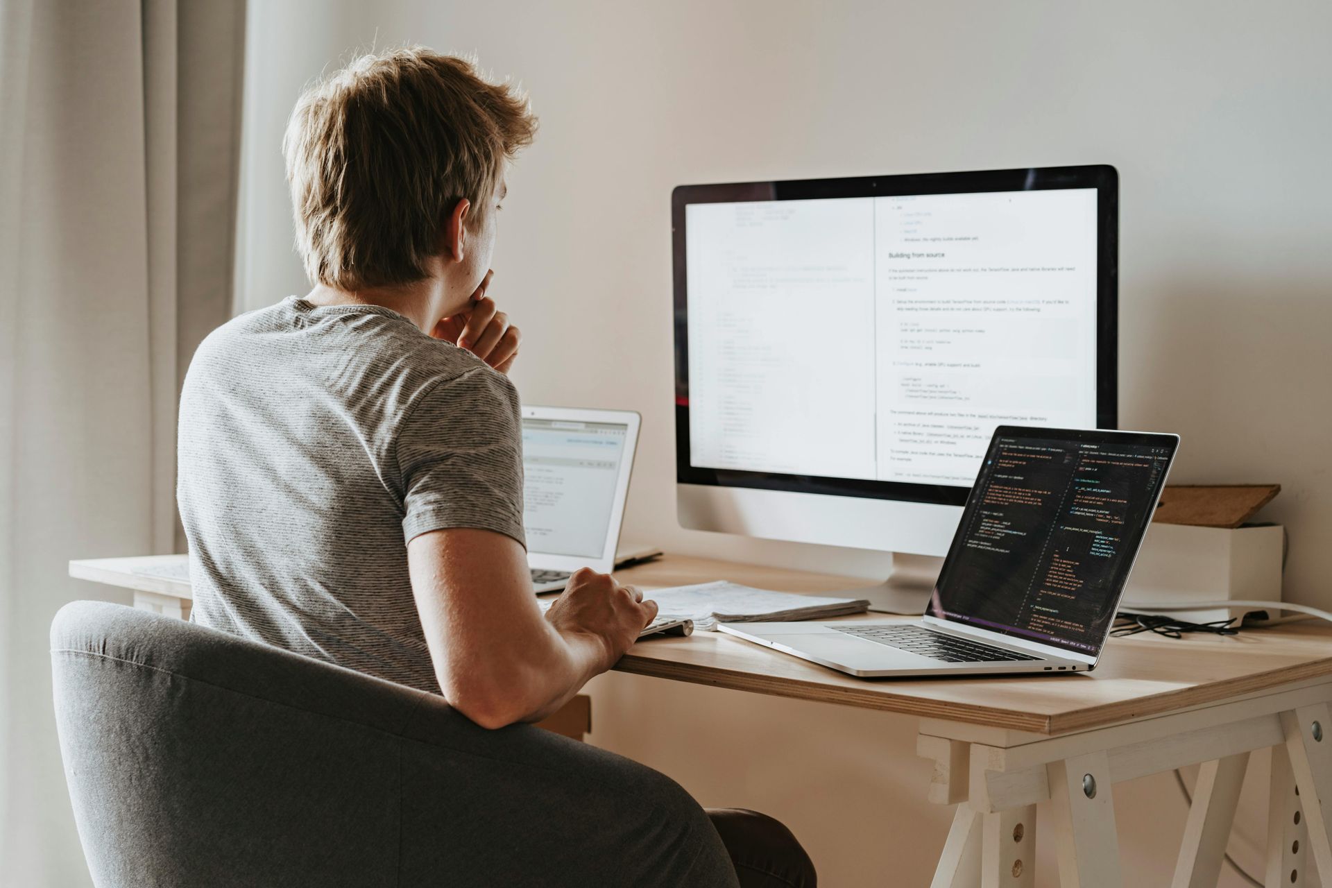 A man is sitting at a desk with a laptop and a computer