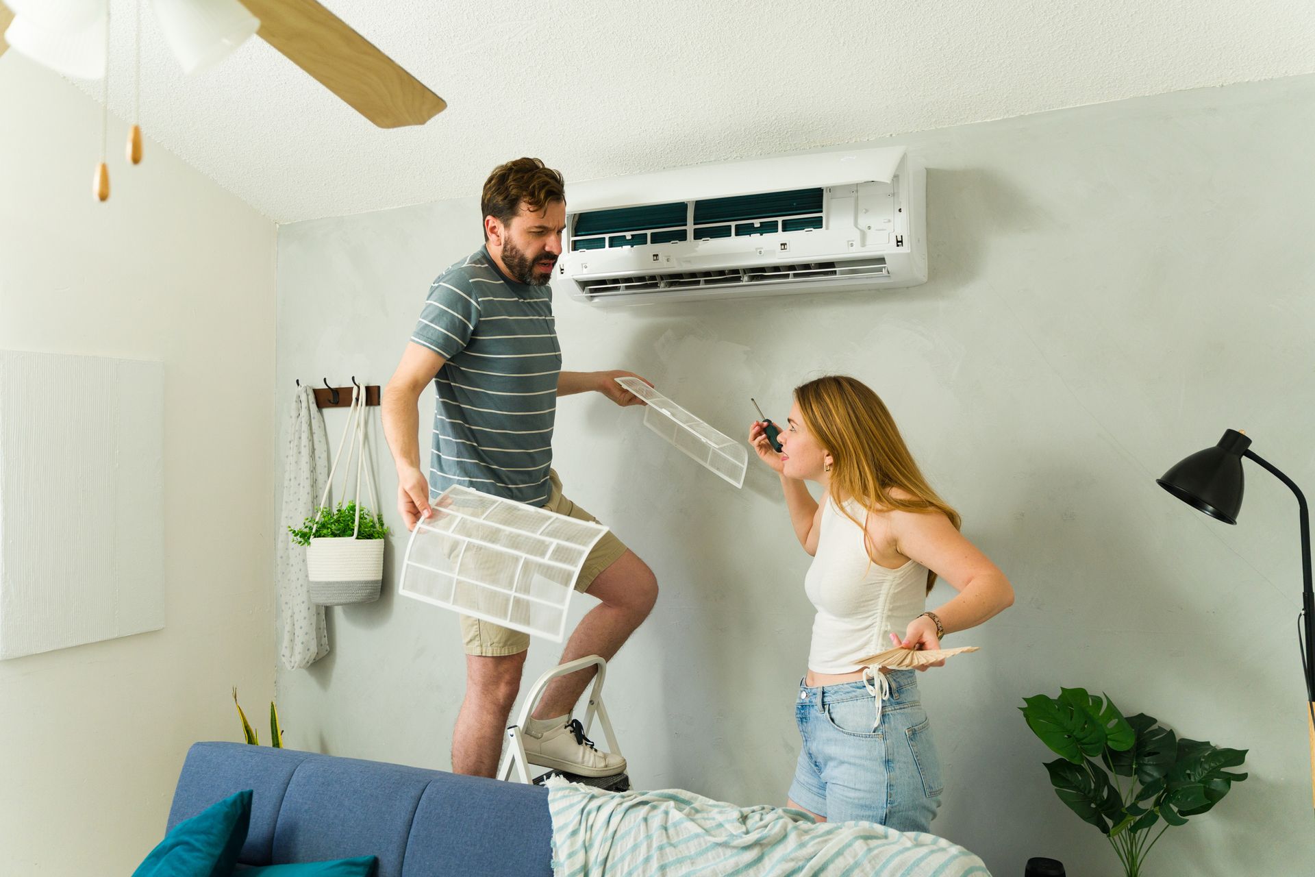 Homeowners replacing a dirty air filter in a wall-mounted mini-split air conditioning unit