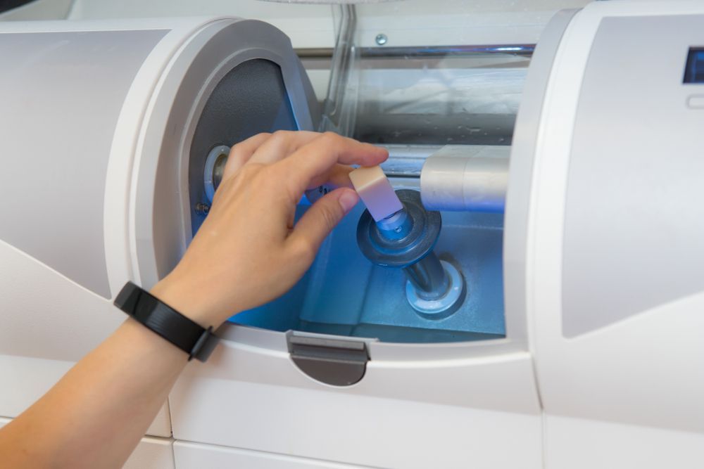Hand Placing a Tooth-colored Ceramic Block Into a Dental Milling Machine — AB Esthetic Dental Laboratory in Brisbane, QLD