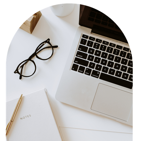 A laptop is sitting on a table next to a notebook and glasses.