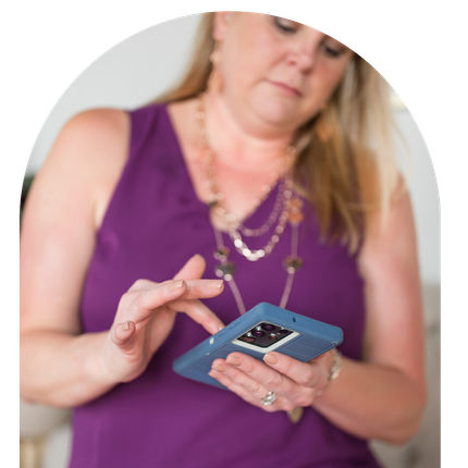 A woman in a purple tank top is holding a cell phone