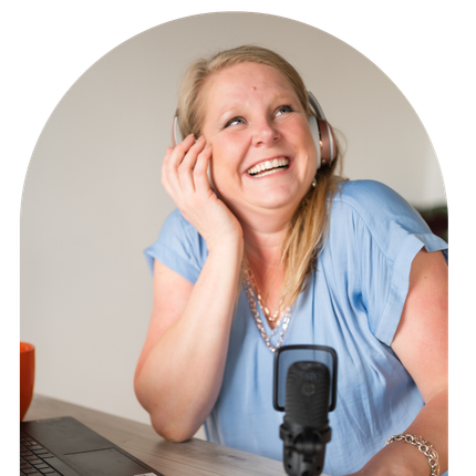 A woman wearing headphones is smiling in front of a microphone.