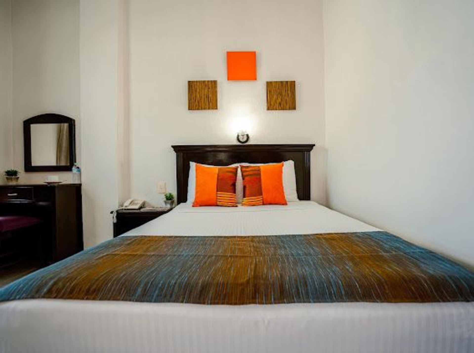 Dormitorio de hotel con cama, escritorio y decoración de pared colorida.