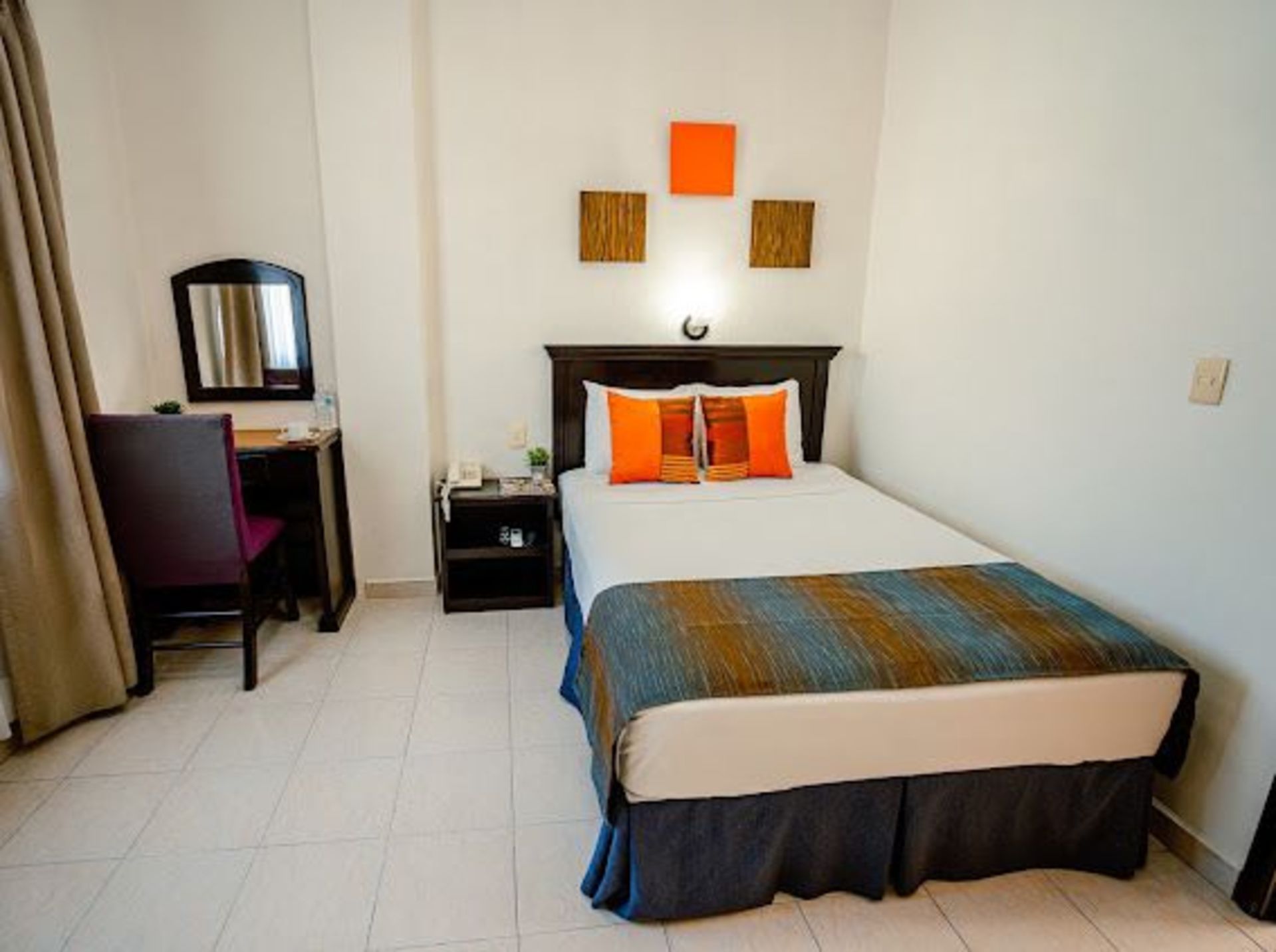 Habitación de hotel con una cama individual, escritorio y arte decorativo en la pared.