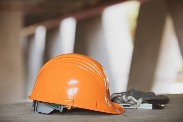 An orange hard hat is sitting on top of a wooden table.- Millville, CA - Concrete Construction Excavating Inc.