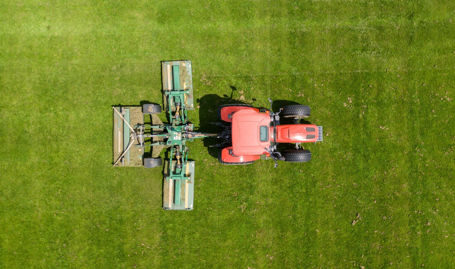 A Man Is Riding A Lawn Mower On A Lush Green Field - Millville, CA - Concrete Construction Excavating Inc.