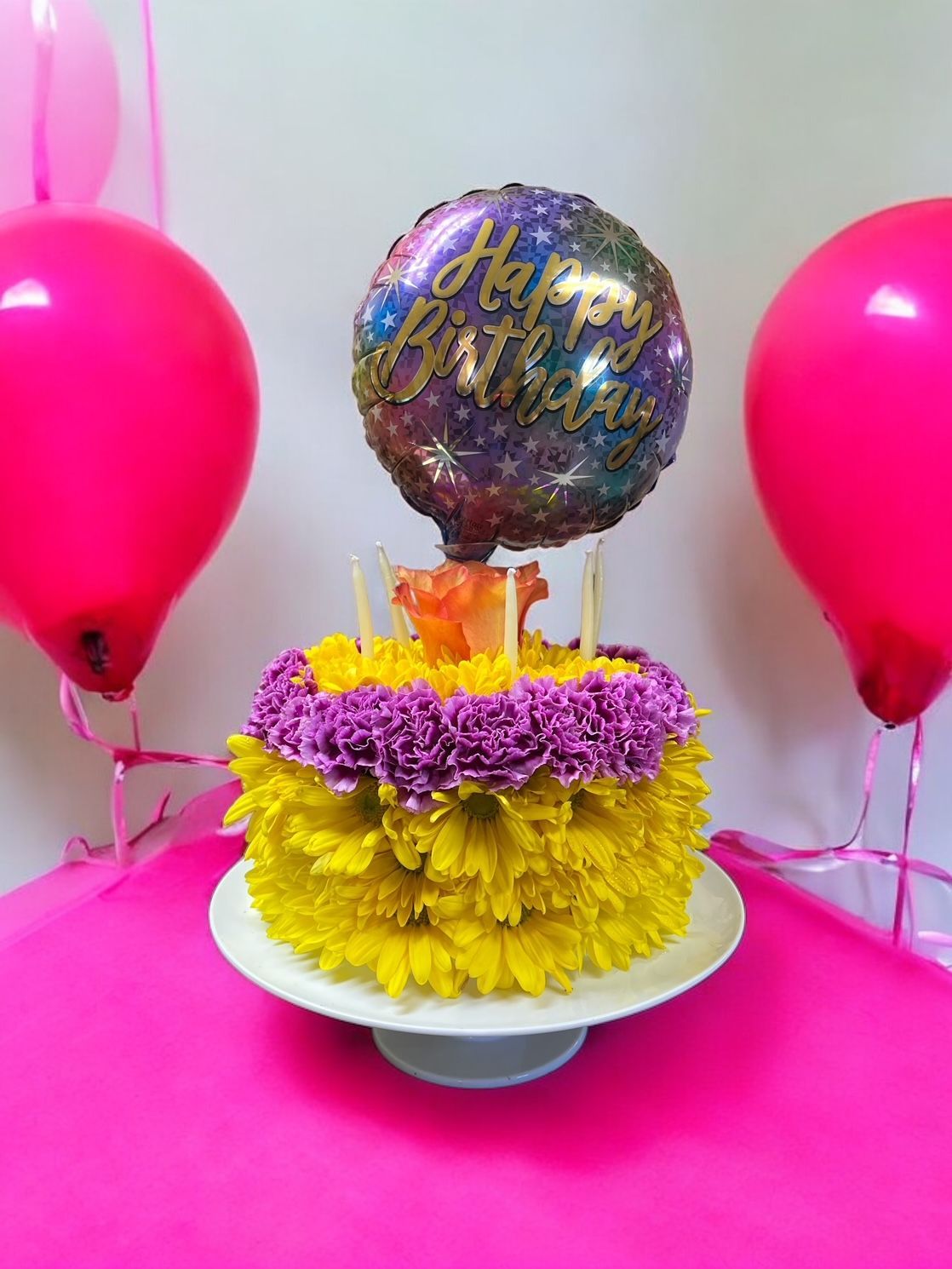 A birthday cake with flowers and a balloon on top of it.