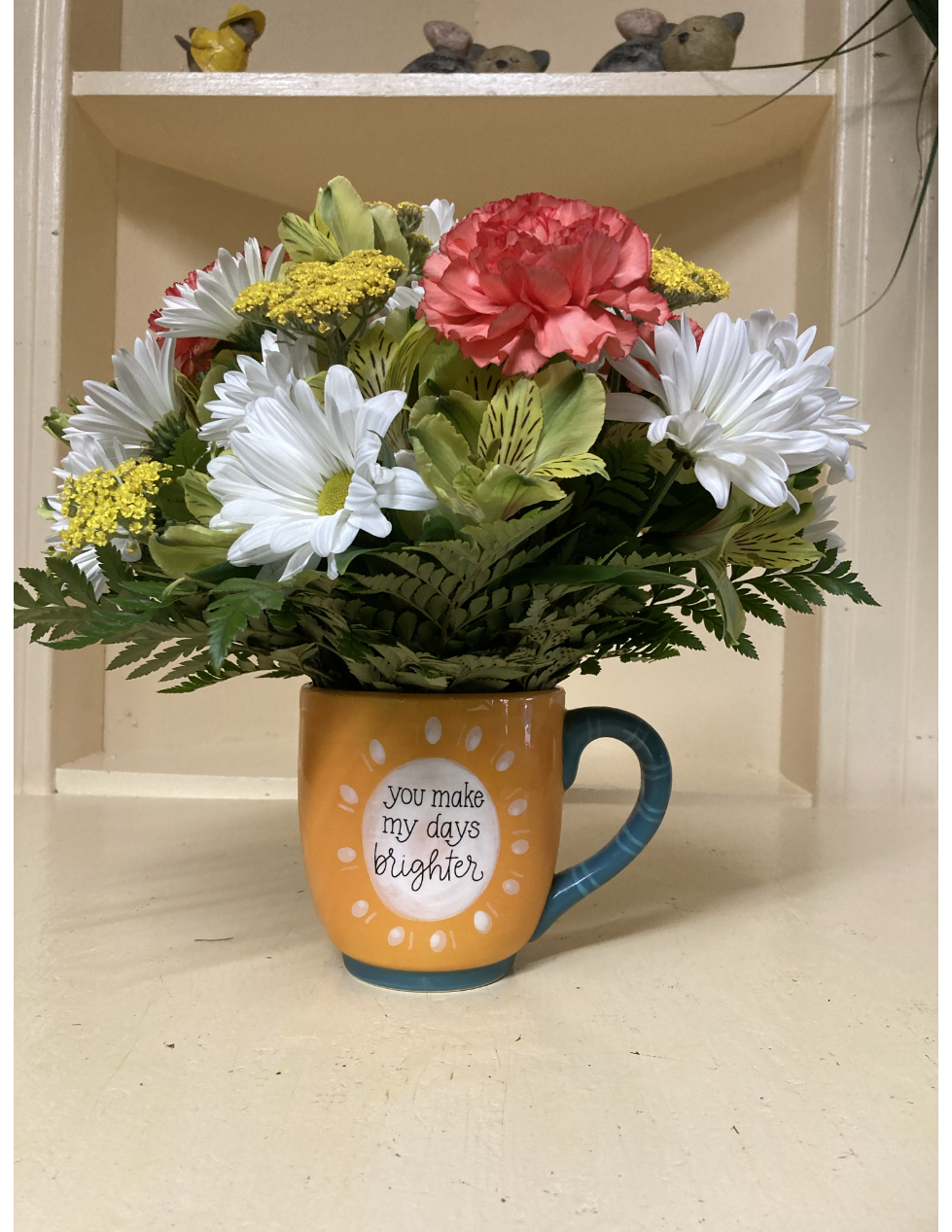A vase filled with pink roses and lilies on a wooden table.