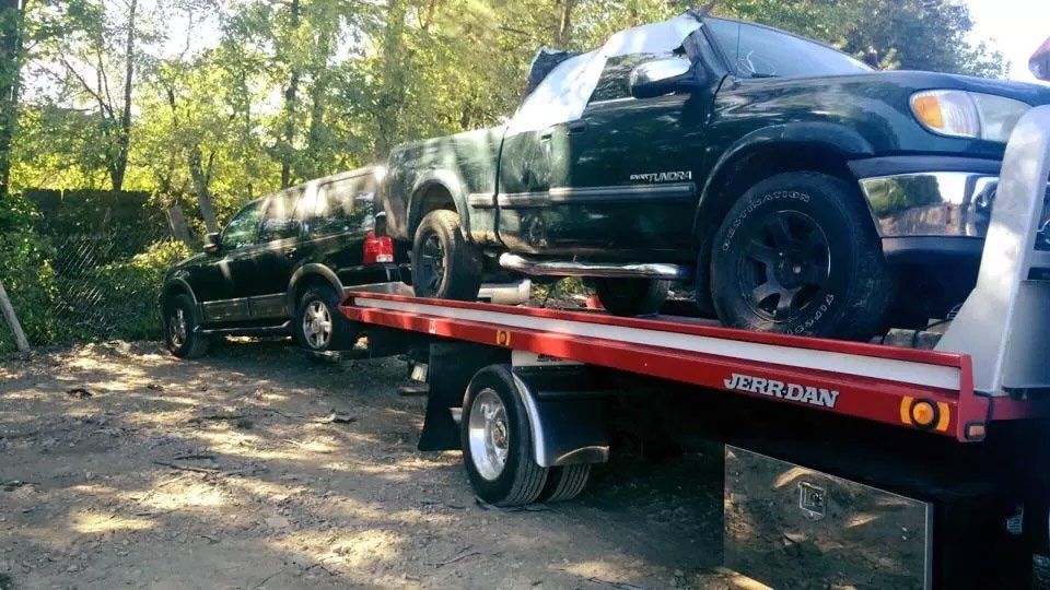 Two trucks are sitting on top of a tow truck.