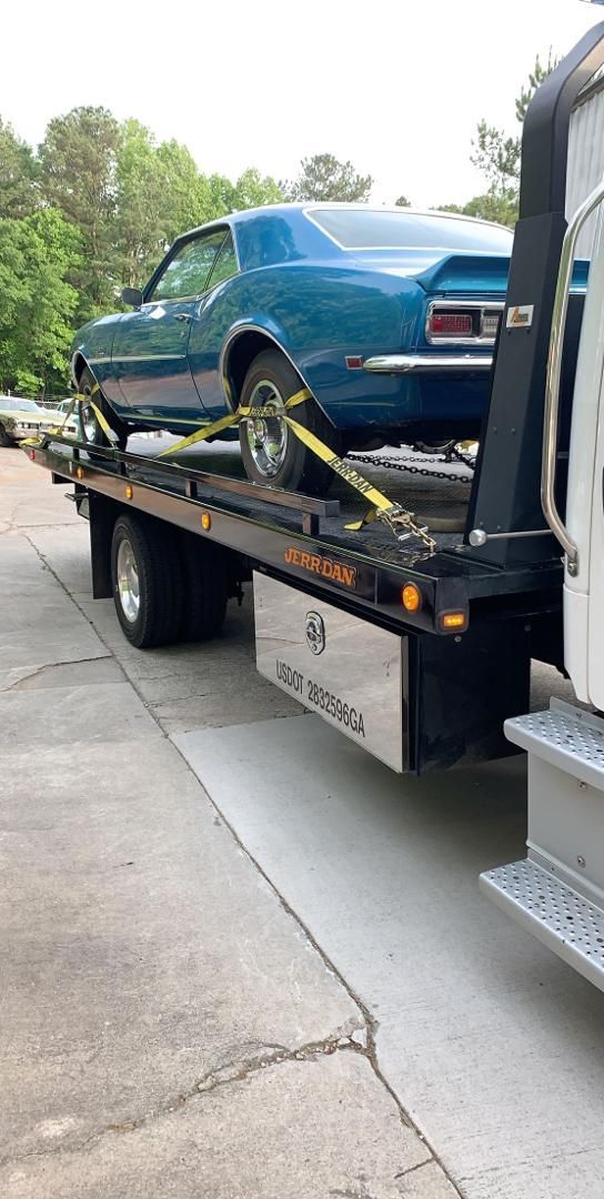 A blue car is being towed by a tow truck.