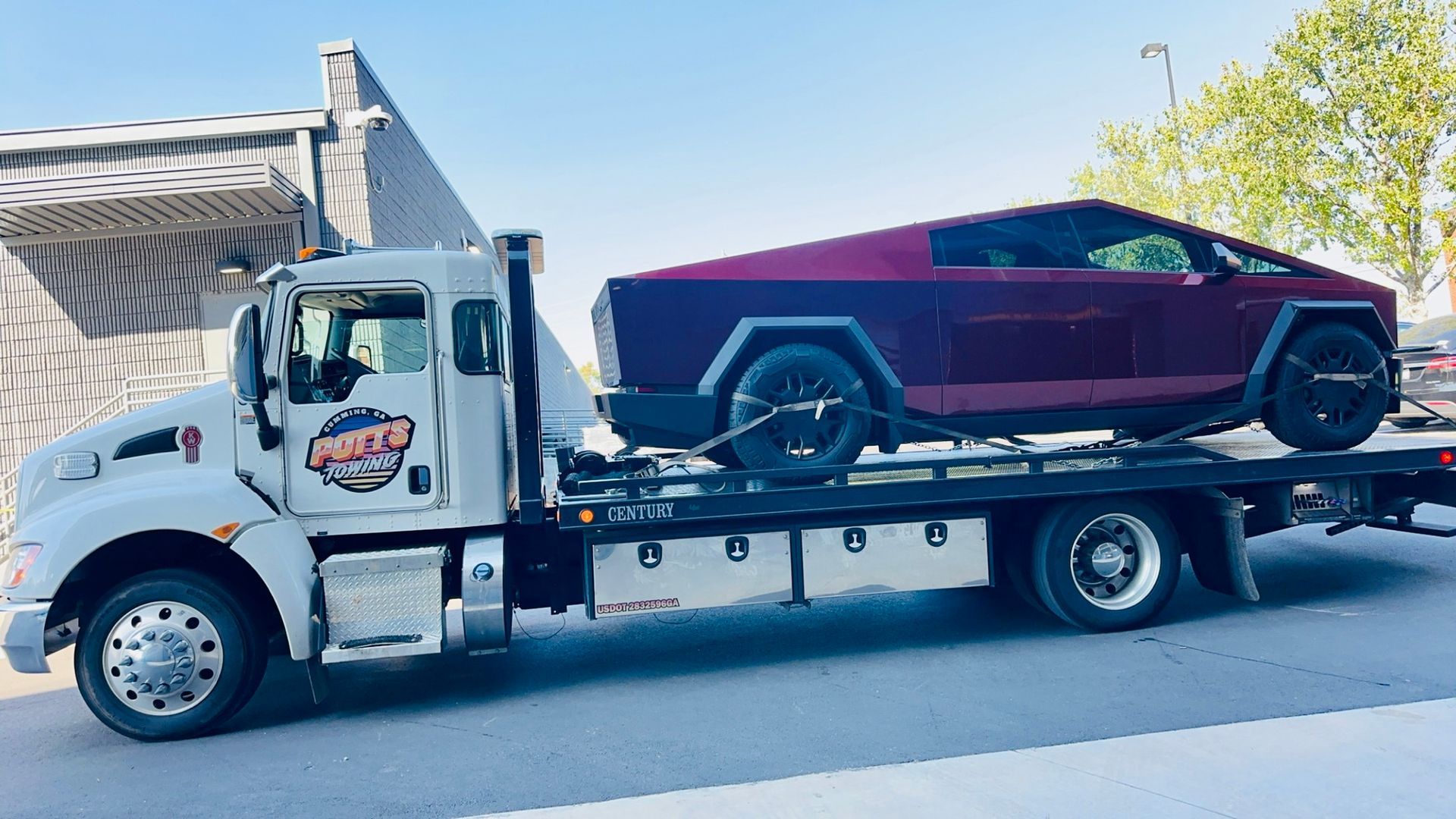 A tow truck is carrying a purple car on the back of it.