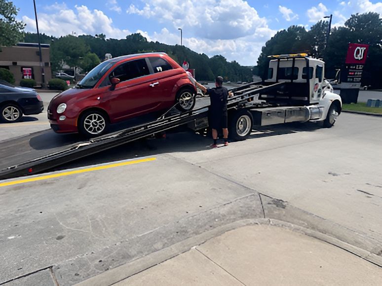 A man is standing next to a red truck and looking at his phone.