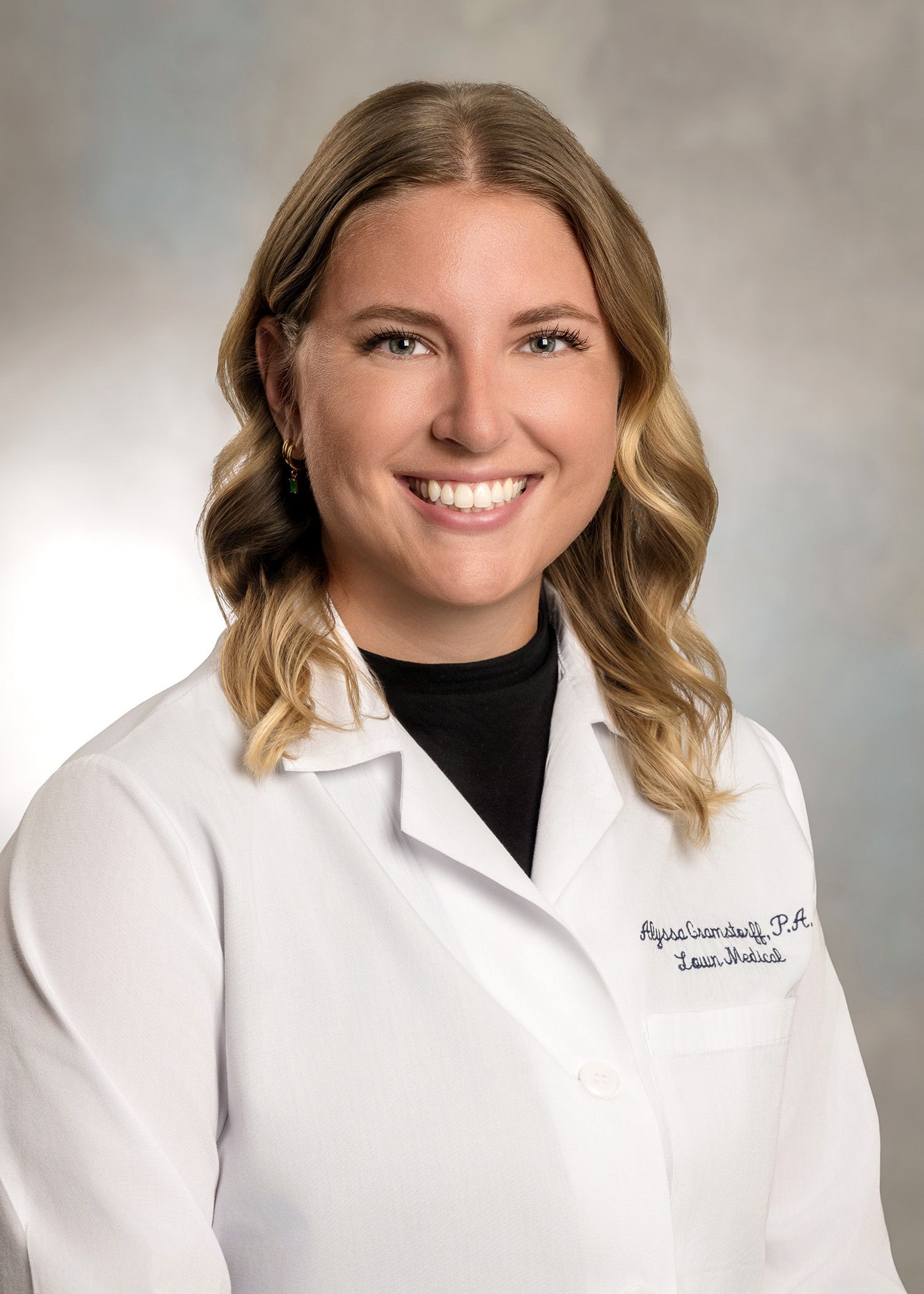 A woman in a white lab coat is smiling for the camera.