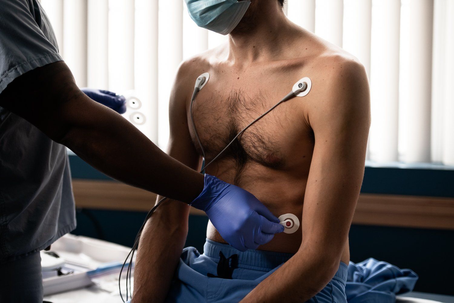 A doctor is examining a man 's chest with a stethoscope.